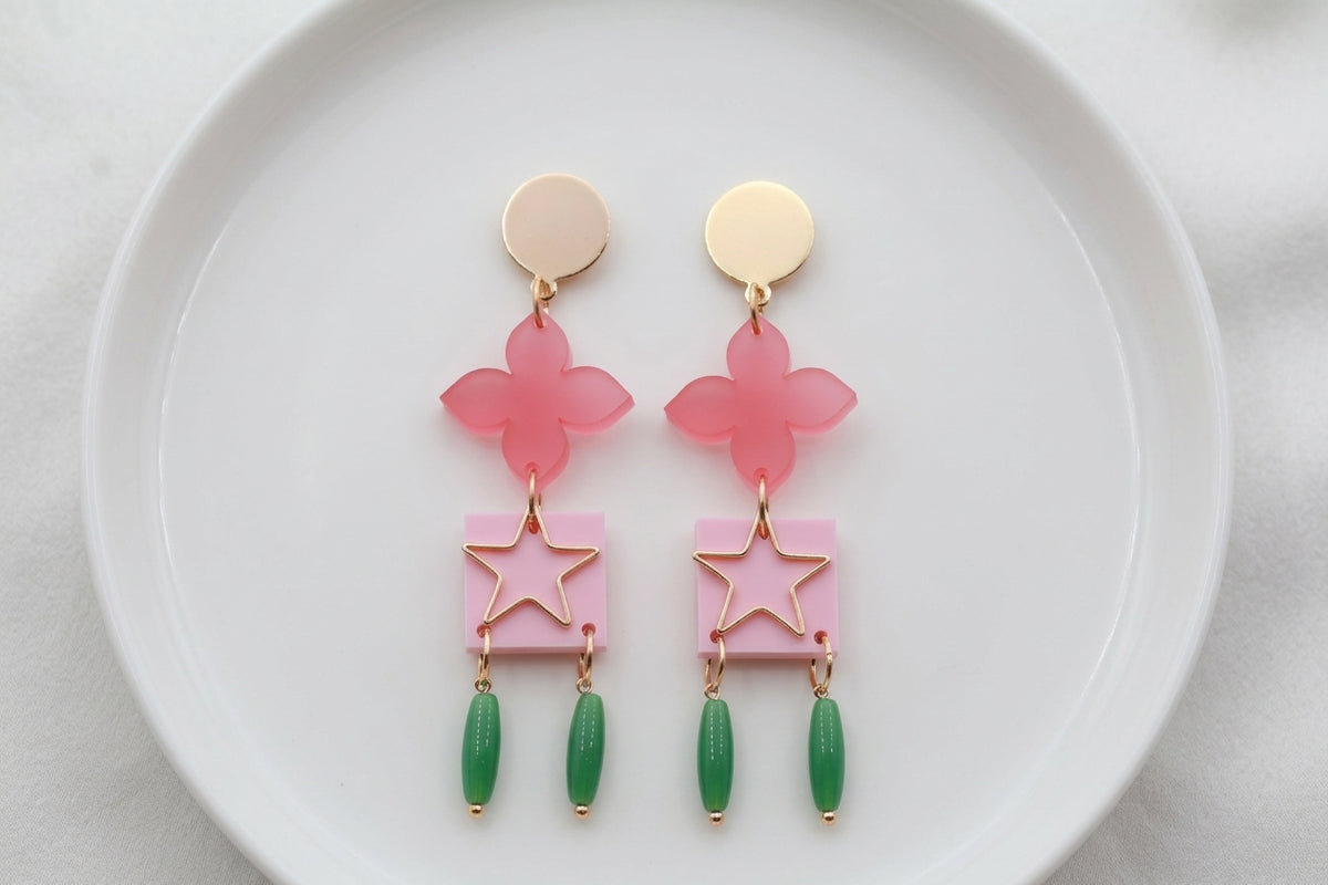 Pink Rose floral star drop earrings arranged on a white plate