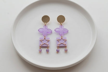 Purple Rose floral star drop earrings arranged on a white plate