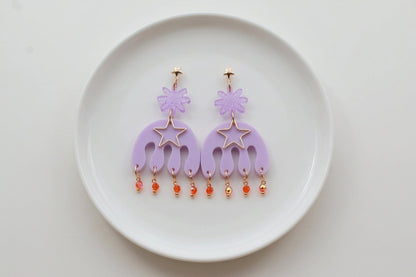 Purple Saar large flower statement earrings arranged on a white plate