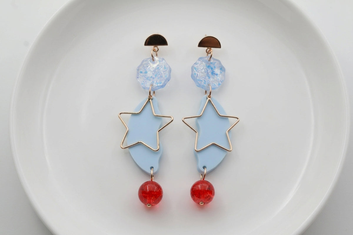 Blue Sara long star dangle earrings arranged on a white plate