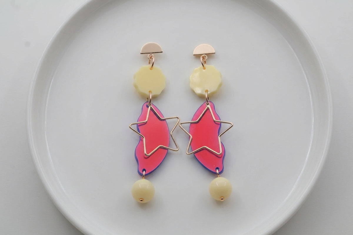 HB Sara long star dangle earrings arranged on a white plate