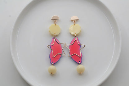 HB Sara long star dangle earrings arranged on a white plate