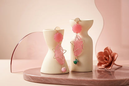 Pink Sara long star dangle earrings in a styled product setting
