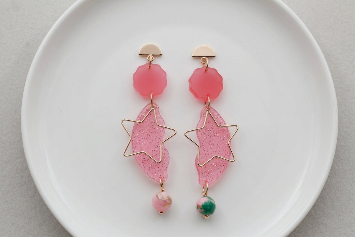 Pink Sara long star dangle earrings arranged on a white plate