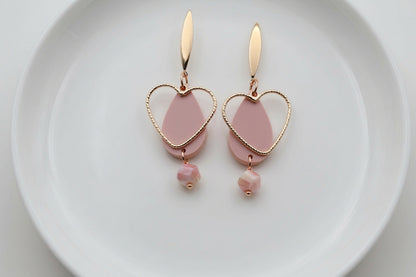 Beige Sofia heart teardrop dangle earrings arranged on a white plate