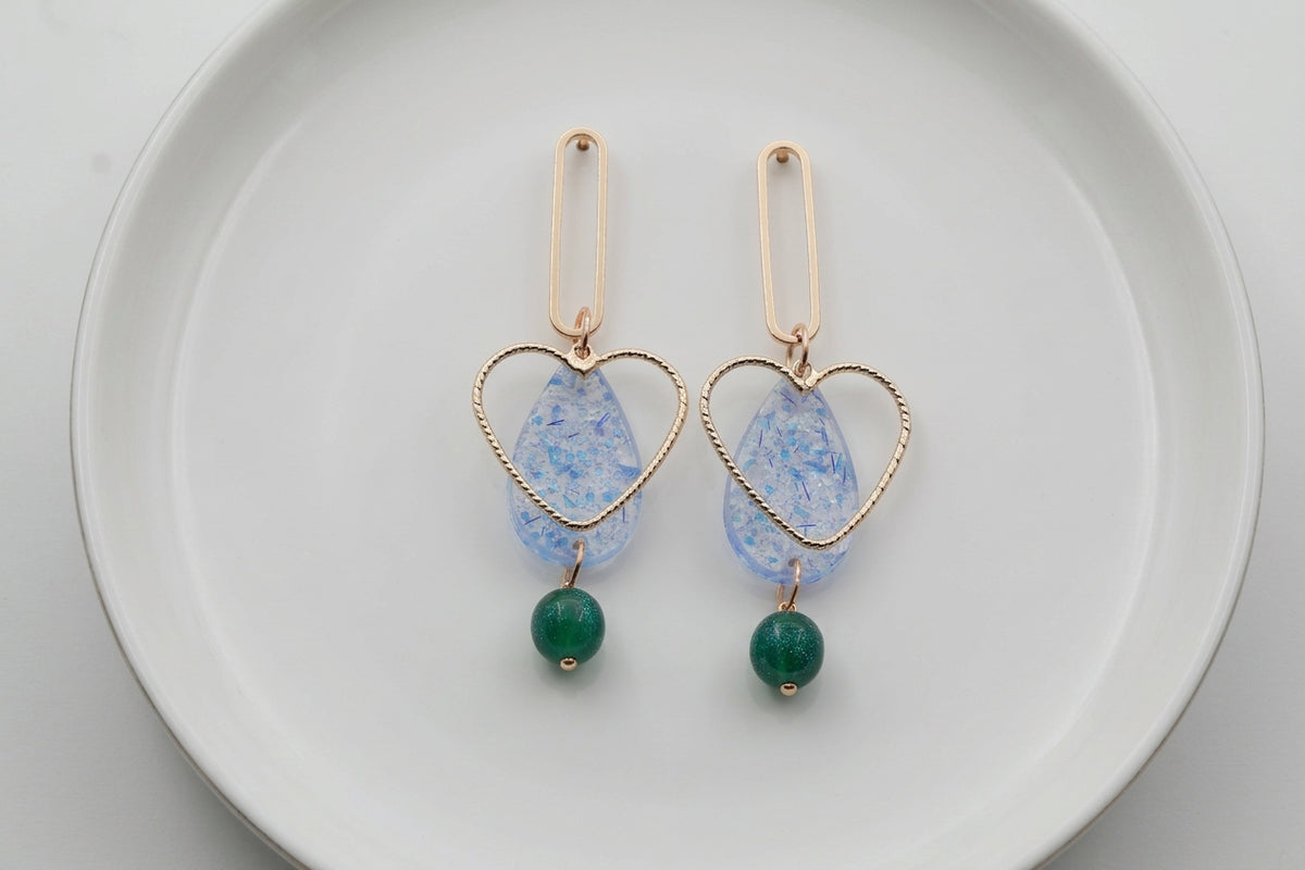 Blue Sofia heart teardrop dangle earrings arranged on a white plate