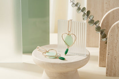 Green Sofia heart teardrop dangle earrings in a styled product setting