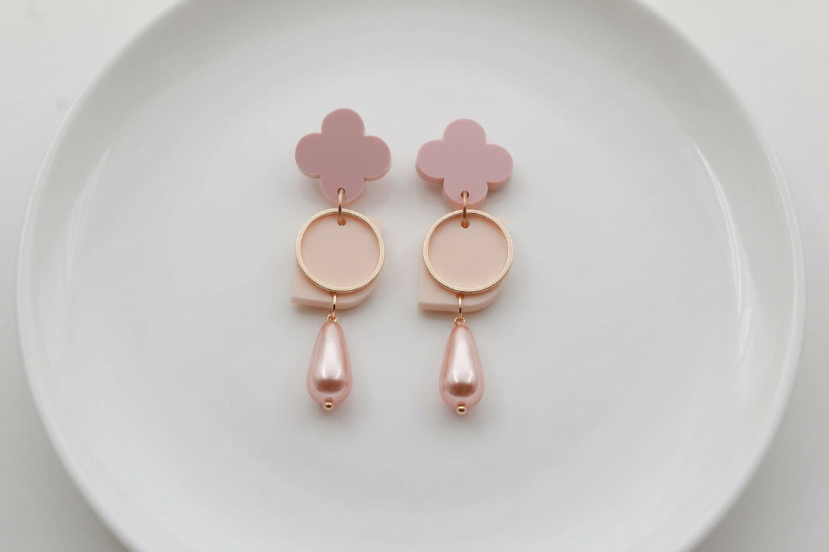 Beige Zoe floral geometric drop earrings arranged on a white plate