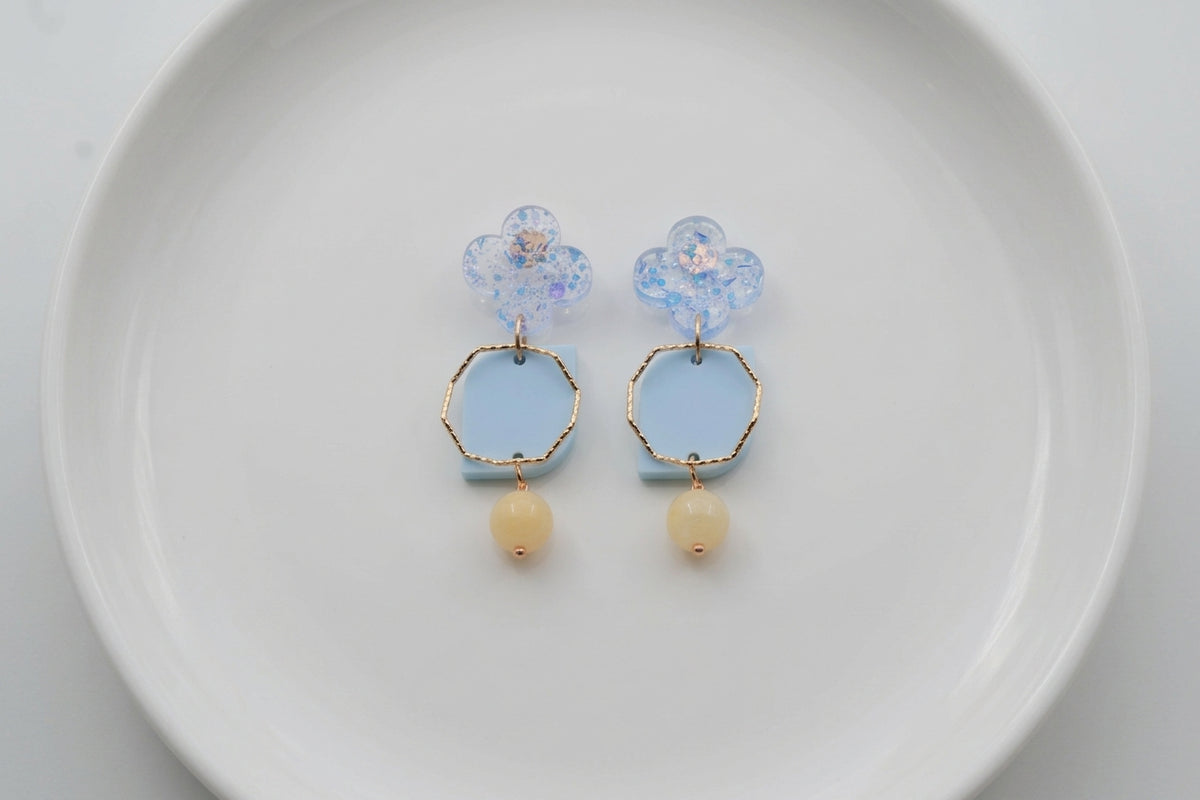 Blue Zoe floral geometric drop earrings arranged on a white plate