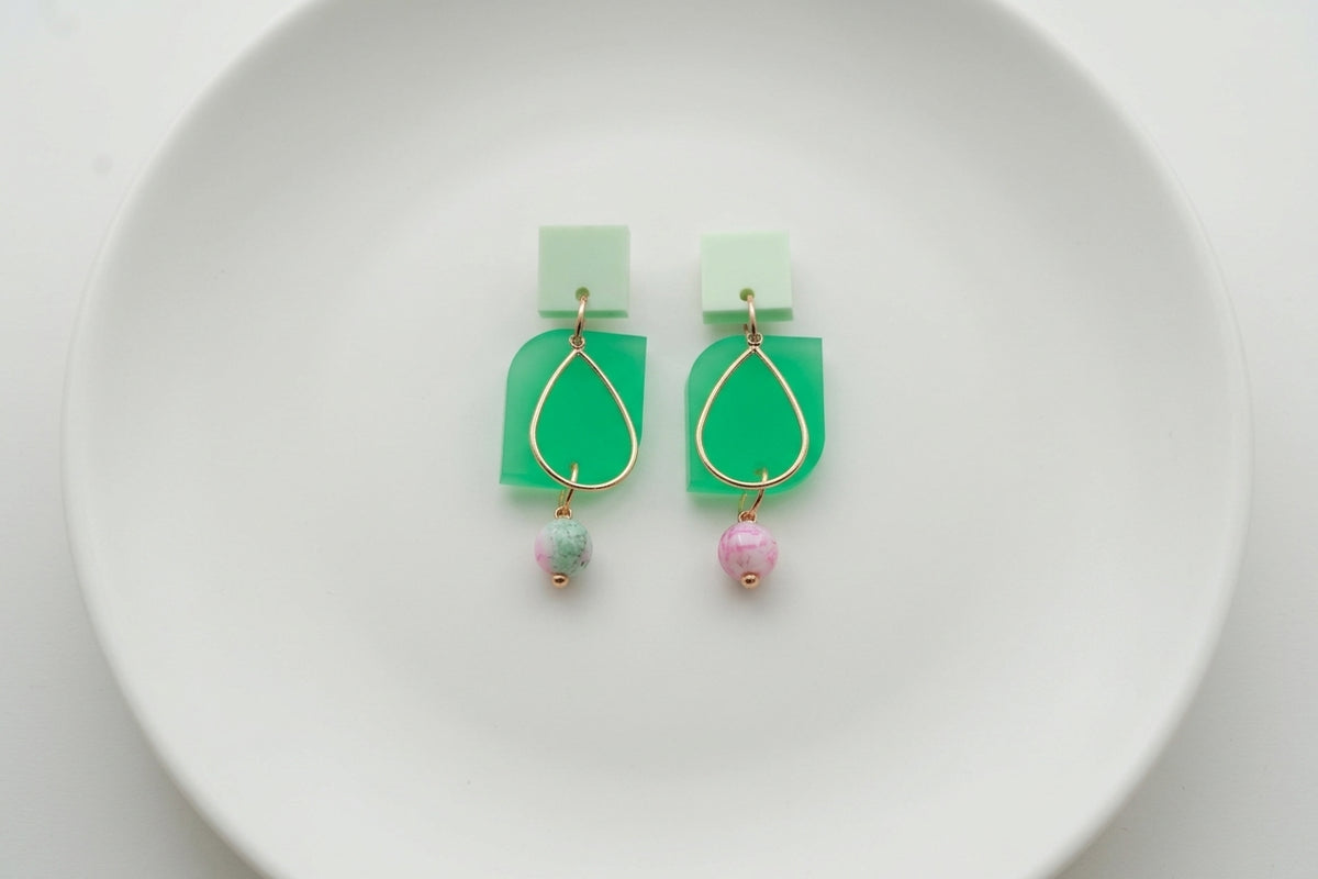 Green Zoe floral geometric drop earrings arranged on a white plate