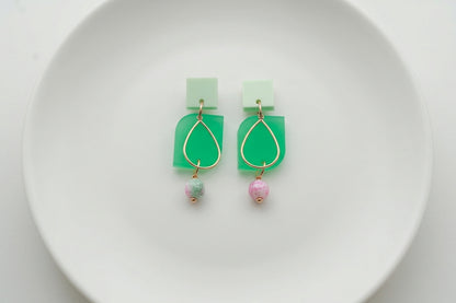 Green Zoe floral geometric drop earrings arranged on a white plate