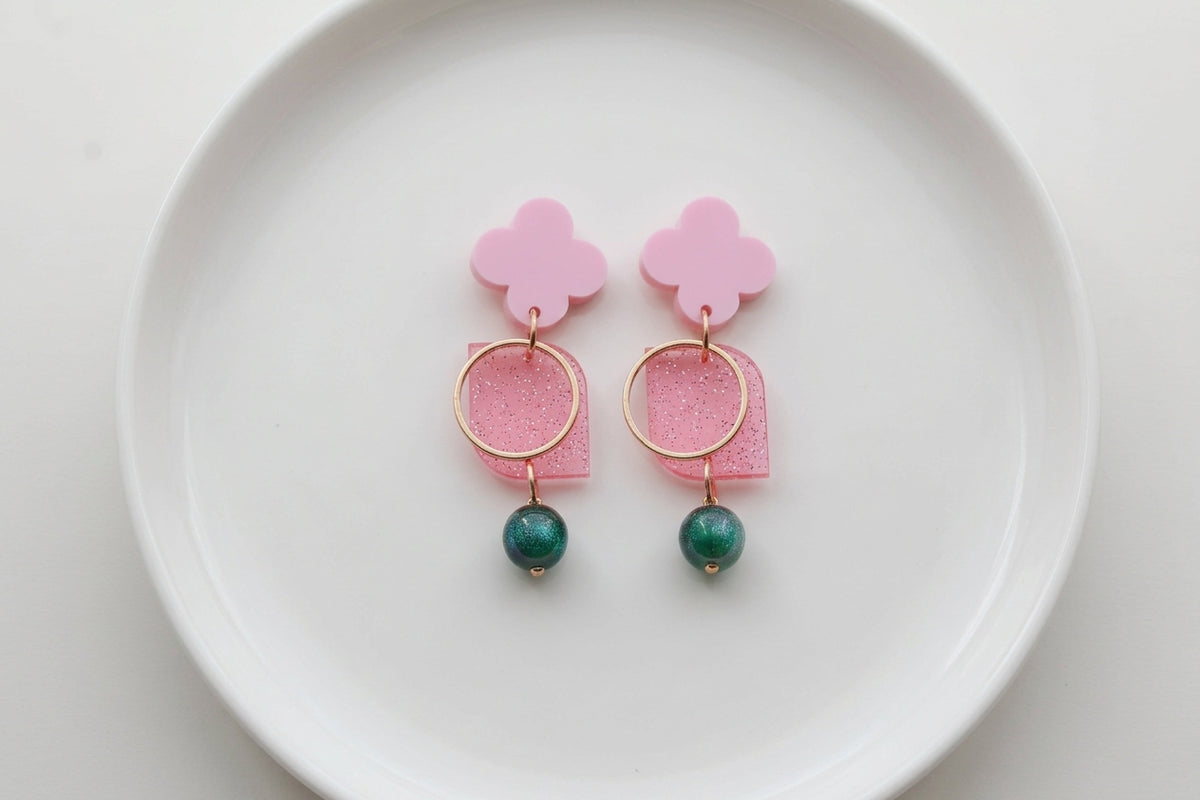 Pink Zoe floral geometric drop earrings arranged on a white plate